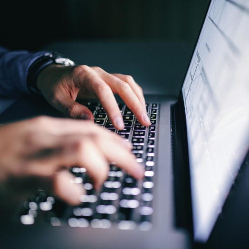 Close up of hands tying on a laptop. Night work concept.