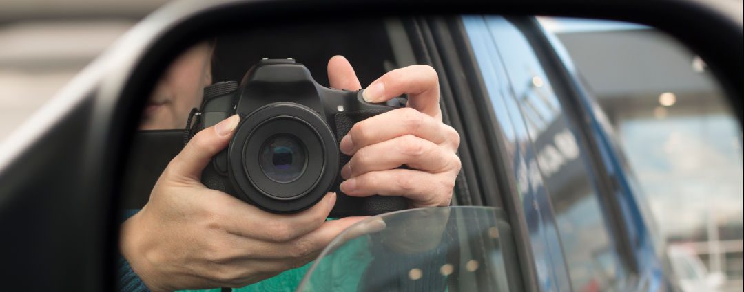 Hidden photographing. Reflection in car mirror of woman with camera.